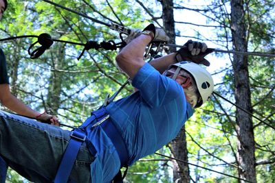 Side view of senior man zip lining in forest