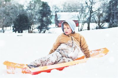 Boy tobogganing on snow during winter