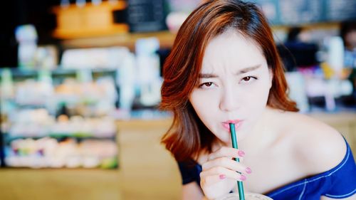 Close-up portrait of young woman drinking in cafe