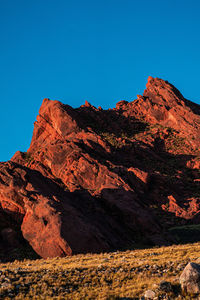 Low angle view of rocky mountains against clear blue sky