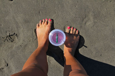 High angle view of disposable cup amidst legs on wet beach