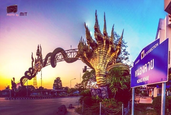 building exterior, built structure, architecture, text, street, western script, illuminated, clear sky, communication, transportation, road, sky, graffiti, outdoors, street light, city, incidental people, blue, palm tree, low angle view