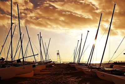 Sailboats moored at harbor against sky during sunset