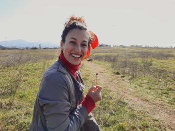 Portrait of young woman standing on field against clear sky