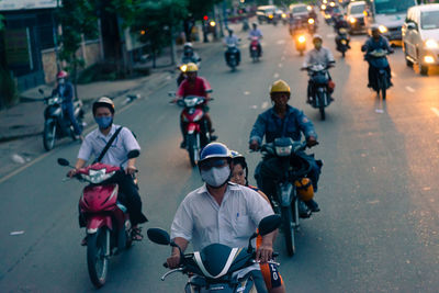 Rear view of people riding bicycle on city street