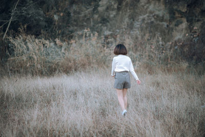 Rear view of woman walking on grassy field