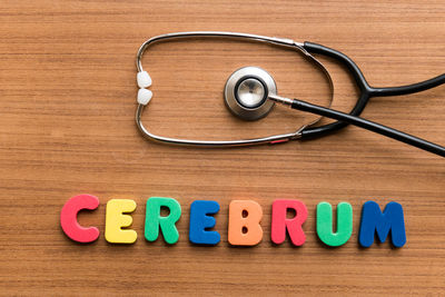Directly above shot of stethoscope with colorful text on wooden table