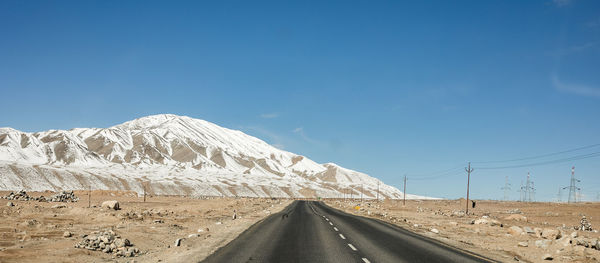 Road by snowcapped mountain against sky