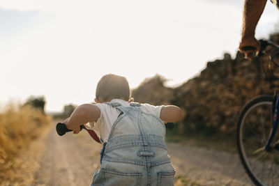 Back view of little boy on bicycle tour with his great-grandfather