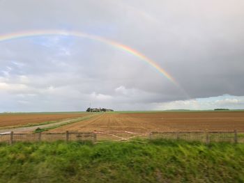 Scenic view of rainbow over field against sky