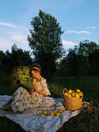 Portrait of young woman sitting on chair against sky