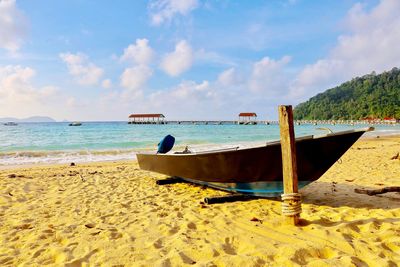 Boat moored on beach against sky