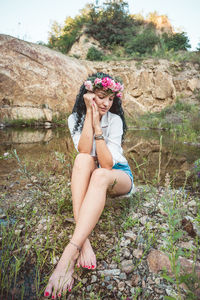 Young woman sitting on rock by the lake 