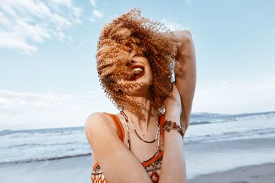 Portrait of woman standing at beach against sky