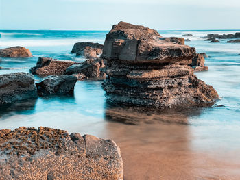 Rock formation on beach against sky