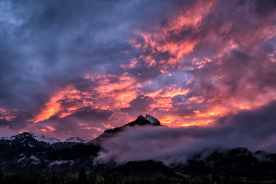 Scenic view of dramatic sky over mountains during sunset