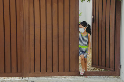 Full length of girl wearing mask standing at entrance