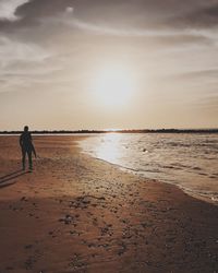 Man on beach against sky during sunset