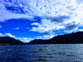 Scenic view of sea and mountains against blue sky