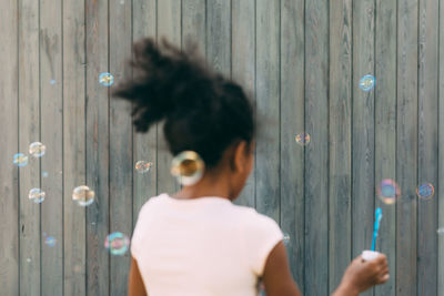 Close-up of woman against wooden wall