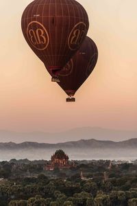 Hot air balloon flying over mountains against sky