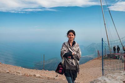 Smiling young man standing on mountain against sky