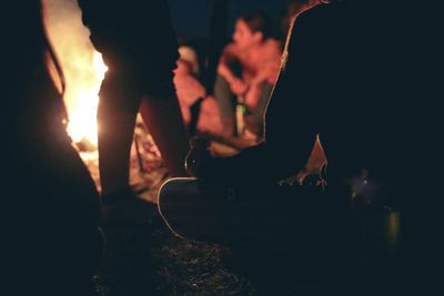 Silhouette people around campfire at night