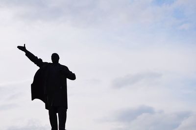 Low angle view of people standing against cloudy sky