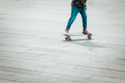Low section of young man skateboarding on street