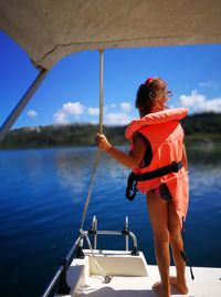 Rear view of woman standing on boat sailing in sea