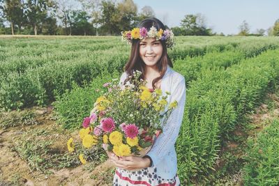 Portrait of woman standing by flower field