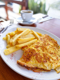 Close-up of omelet with french fries served in plate on table