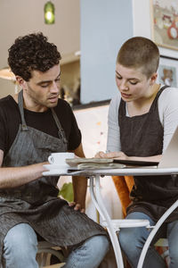 Male and female owners discussing with each other sitting at cafe