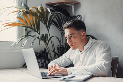 Side view of man using laptop at home