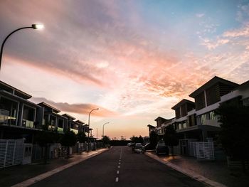 Street amidst buildings against sky during sunset