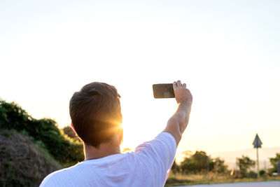 Portrait from behind of man taking selfie during sunset