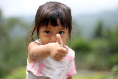 Portrait of cute girl showing thumbs up