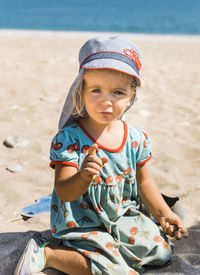 Cute girl sitting on sand at beach