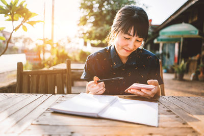 Young woman using mobile phone on table