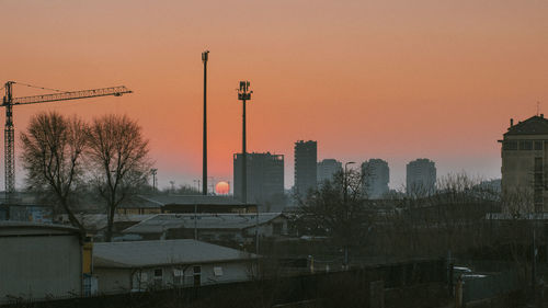 Buildings in city against clear sky during sunset