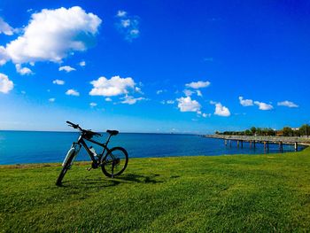 Bicycle by sea against blue sky