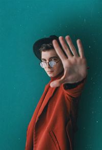 Portrait of young man standing against blue wall