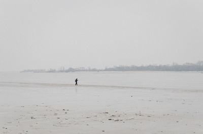 Mid distance view of man walking at beach against sky