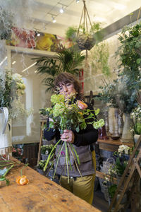 Senior woman preparing bouquet of flowers at flower shop desk