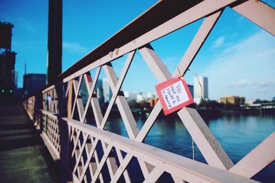 Low angle view of padlocks hanging on railing against sky