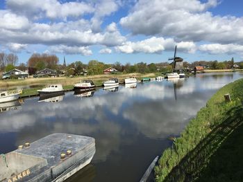 Boats moored in sea against cloudy sky