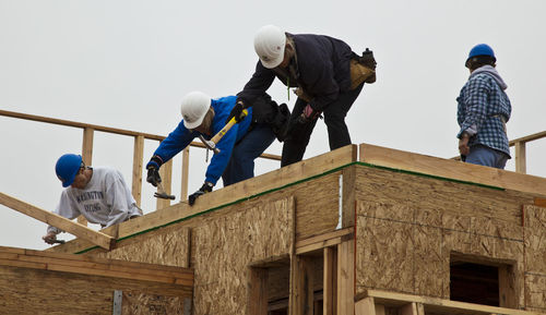 Low angle view of people working at construction site against sky