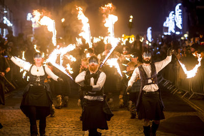 Group of people walking on illuminated street at night