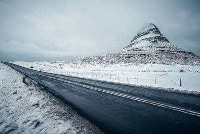 Road by snowcapped mountain against sky