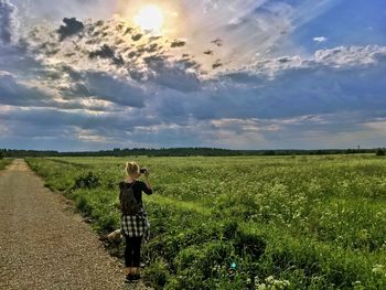 Woman photographing on field against sky